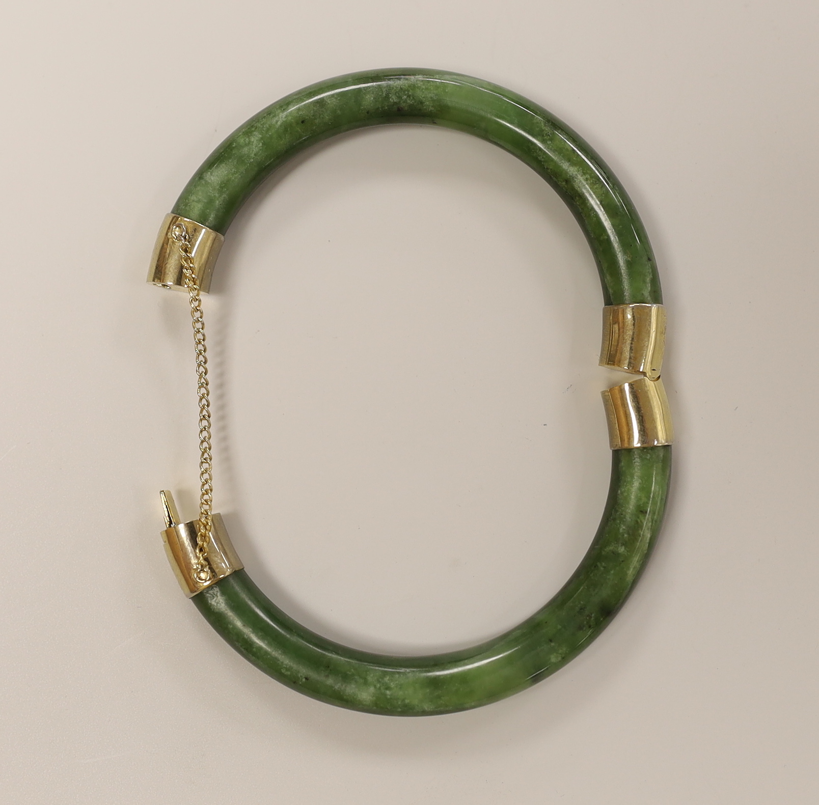 A spinach green jade bangle with metal mounts, 8.5 cm diameter (outer edge to edge)